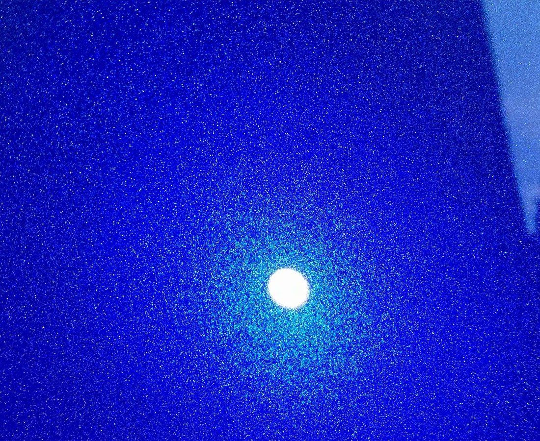 Bright white light glowing against a deep blue, speckled background.