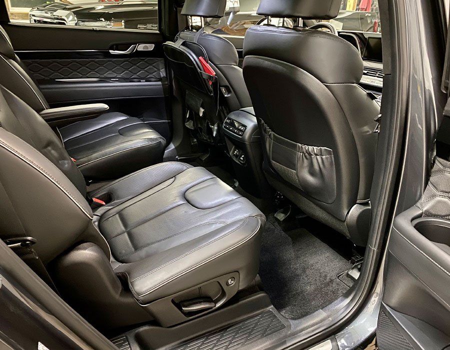 Black leather car interior with rear seats and open door, showing a clean, spacious cabin.