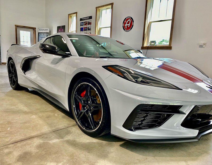 Silver sports car parked in a showroom, front three-quarter view with black wheels and red brake calipers