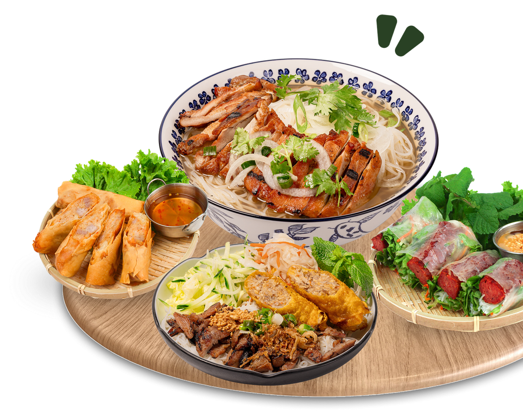 Un assortimento di piatti vietnamiti su un vassoio rotondo, tra cui carne alla griglia, noodles, involtini primavera e verdure fresche.