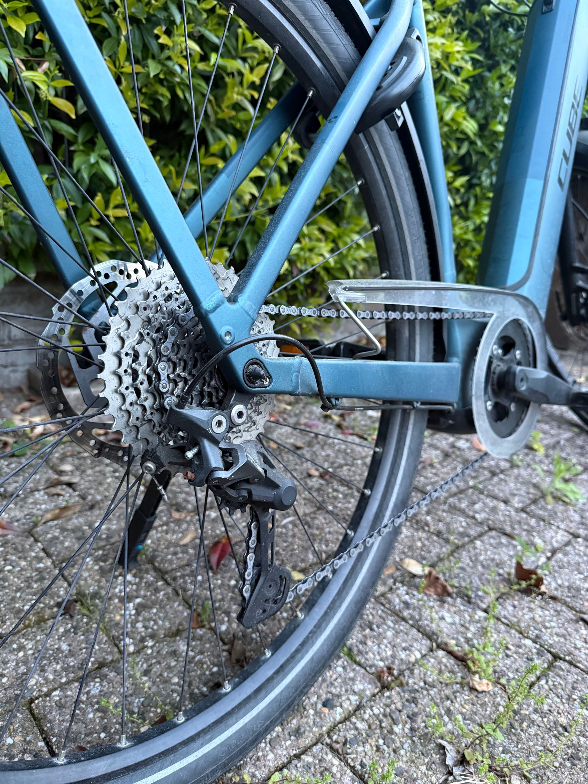 Handen die een fietsketting en versnellingen schoonmaken met een borstel en een fles reinigingsmiddel.