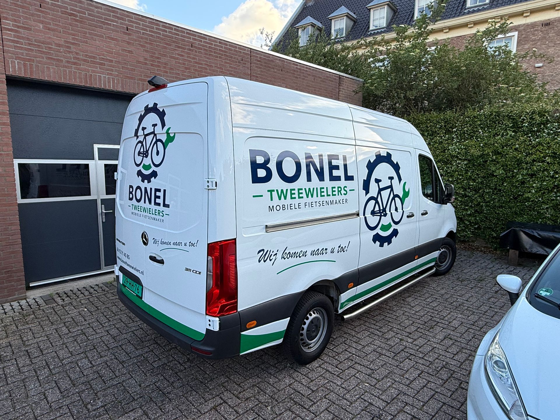 De belettering van de BONEL Techniciens-bestelwagen in wit en blauw, weergegeven vanuit zij-, voor- en achteraanzicht.