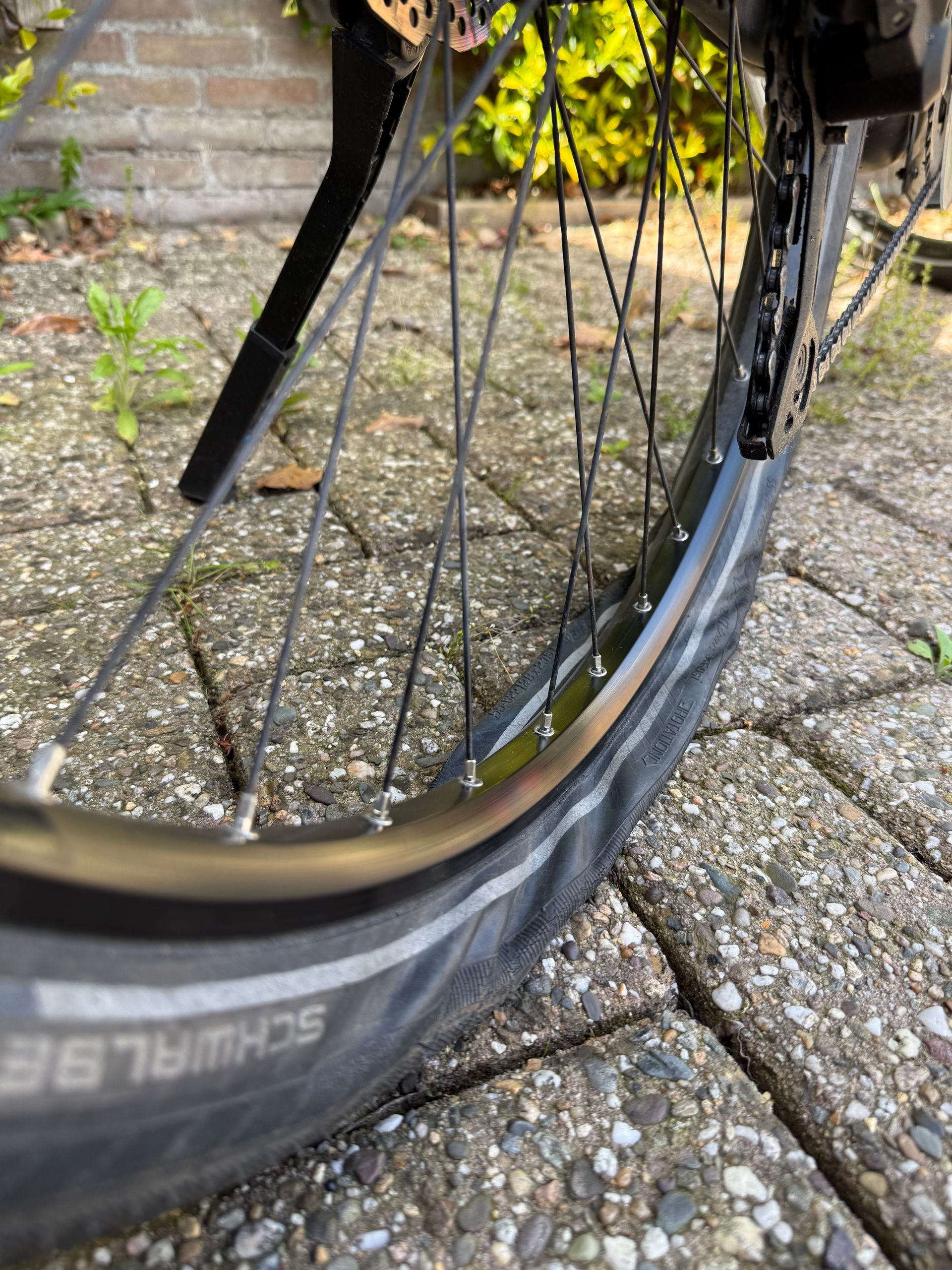 Een lekke fietsband op een hobbelig pad, waarbij de velg bijna de grond raakt.