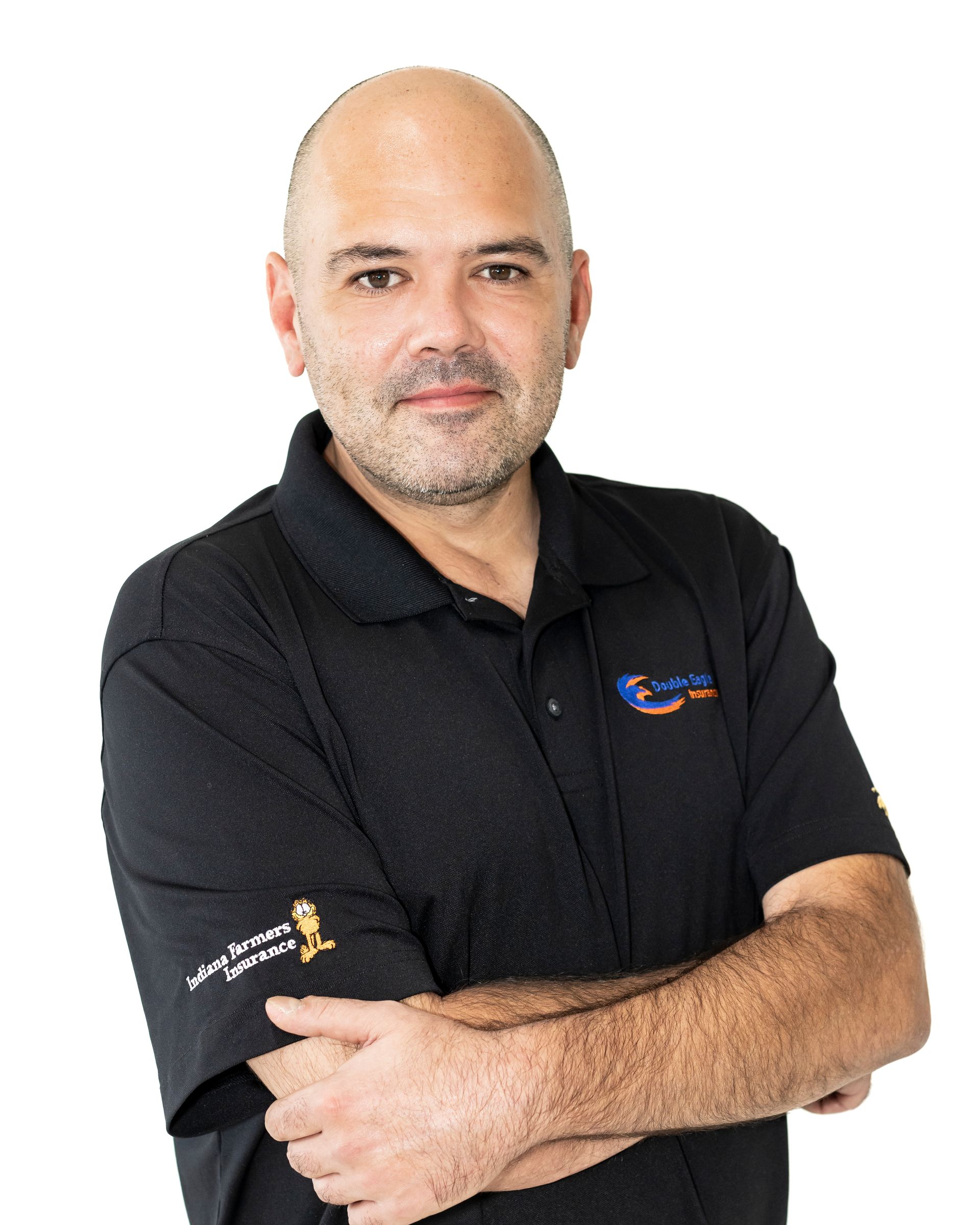 A bald man with a beard is wearing a black polo shirt with his arms crossed.