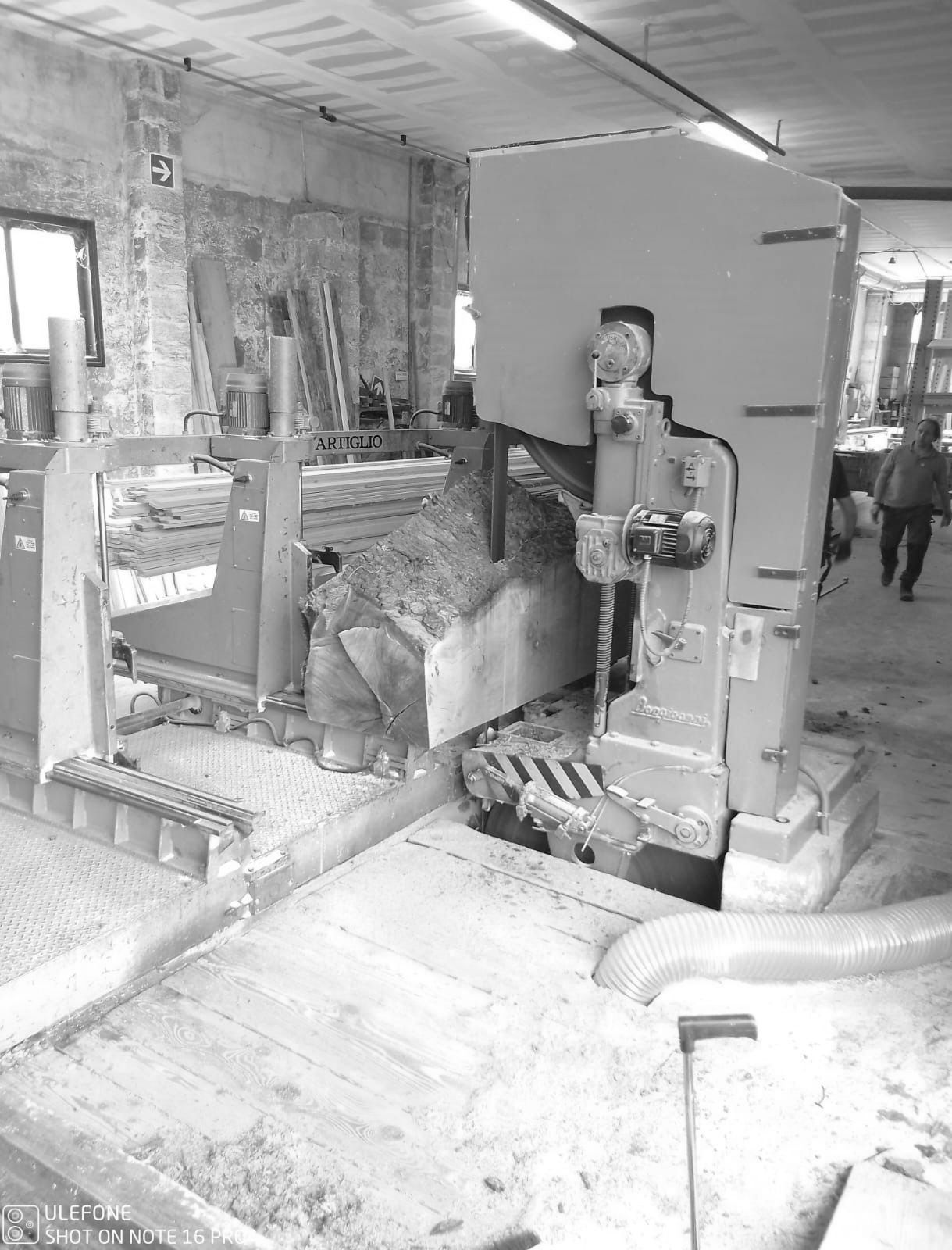 Macchinario industriale all'interno di un'officina polverosa con una persona in piedi accanto ad esso.