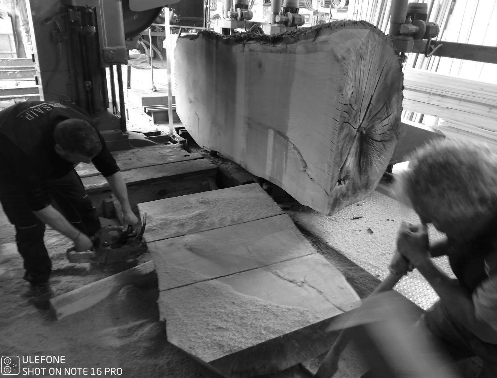 Operai che movimentano grandi lastre di pietra in un'officina industriale, con un carrello elevatore nelle vicinanze.
