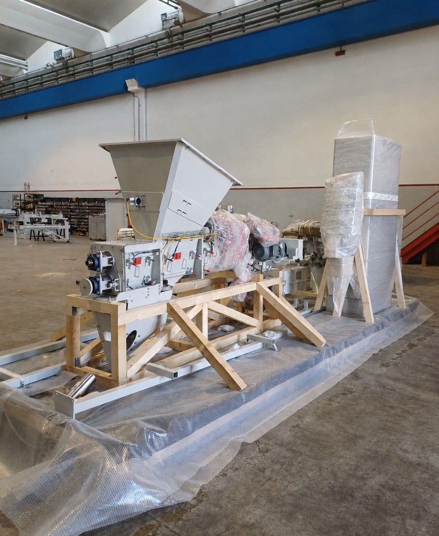 Macchinario industriale su slitte di legno, avvolto nella plastica, in un magazzino