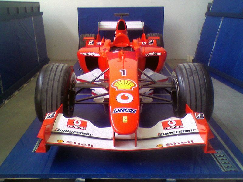 Una monoposto di Formula 1 rossa vista frontalmente in un box blu.