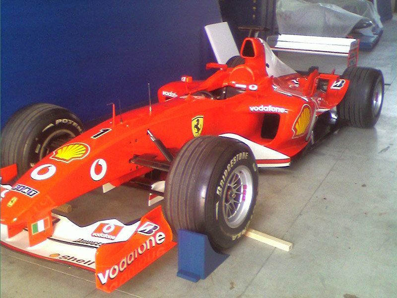 Una Ferrari di Formula 1 rossa in un garage, vista dalla parte anteriore sinistra.