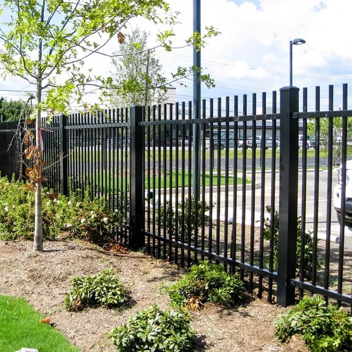 Black wrought iron fence with decorative swirls, blurred background.