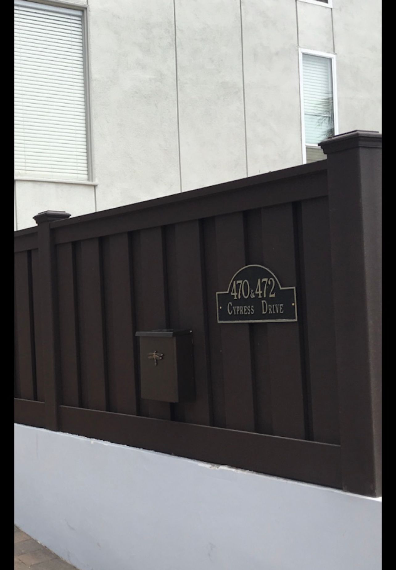 Brown fence with a mailbox and house number sign that reads 
