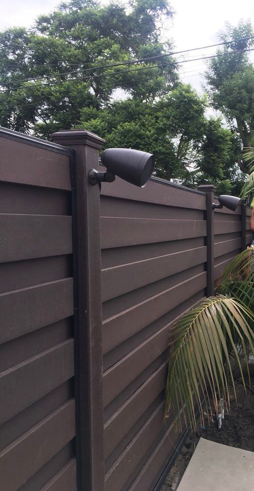 Brown metal fence with vertical ribbed panels, outdoors.