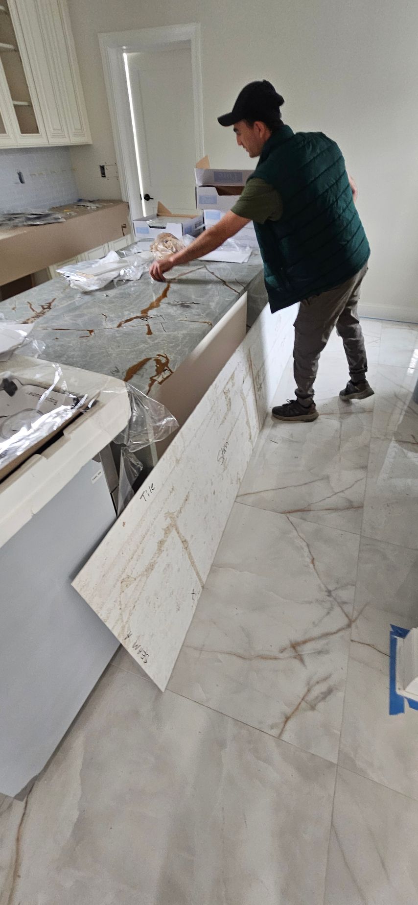 Worker installing a white countertop in a kitchen under renovation