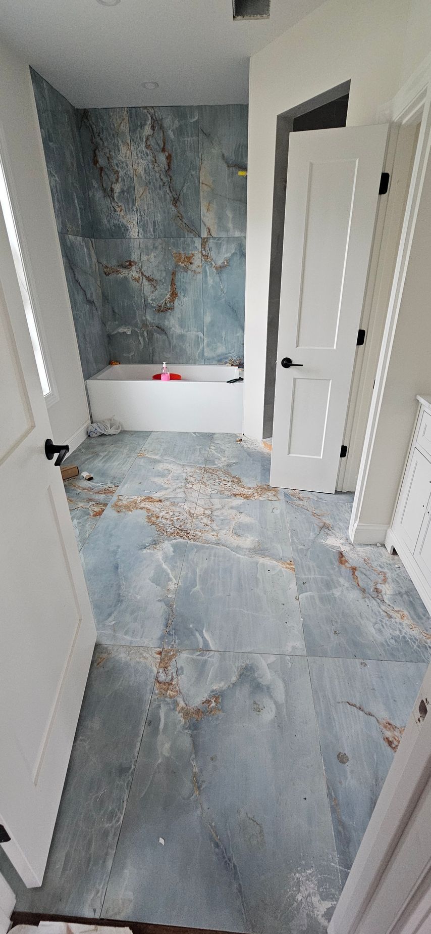 Damaged hallway with cracked blue flooring, peeling walls, and debris scattered across the floor.