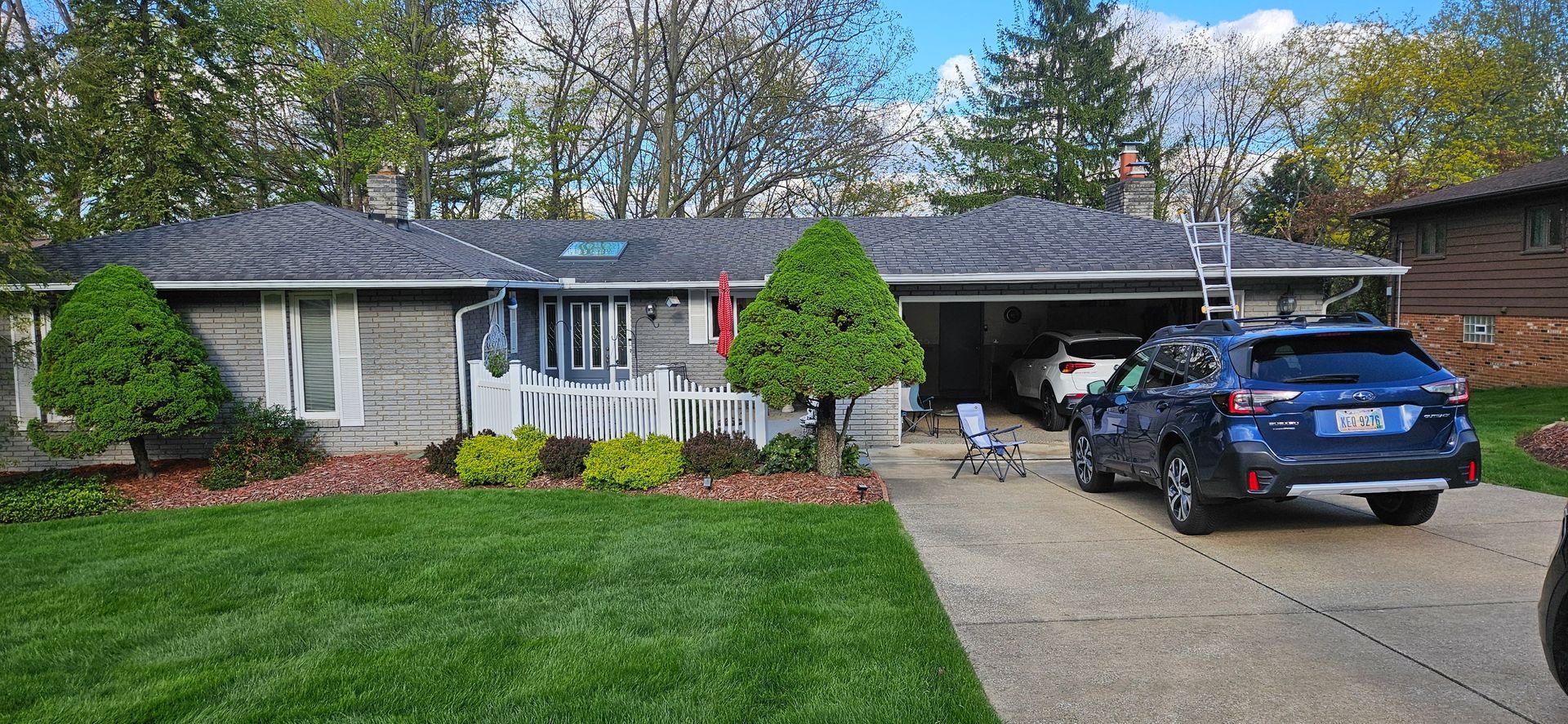 Suburban house with a blue SUV in the driveway, front lawn, and covered porch
