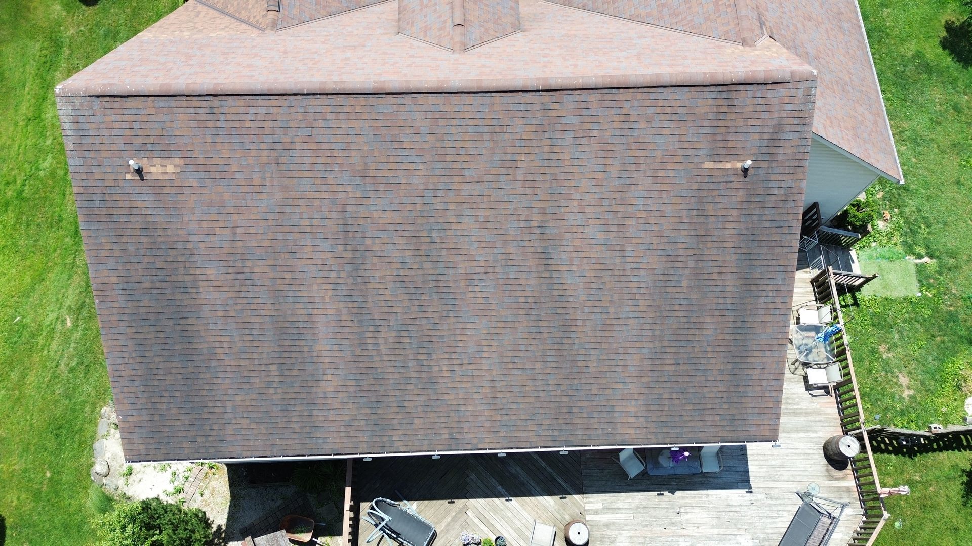 Aerial view of a house with a large gray roof and small yard below