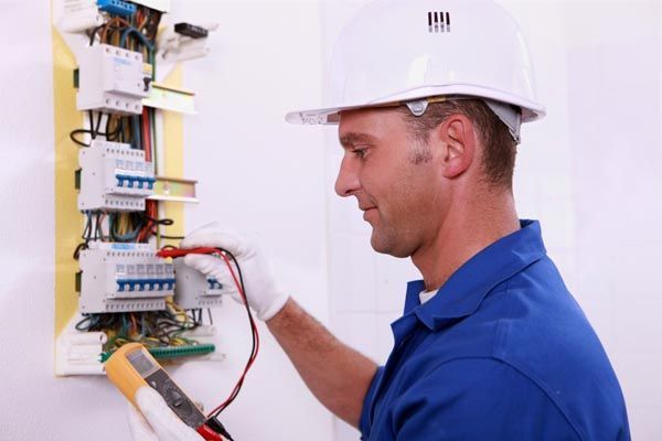 Licensed electrician testing voltage on a commercial fuse board.