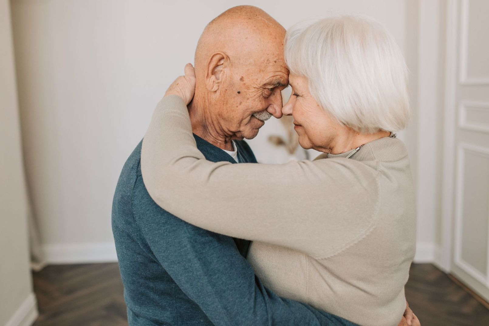 Two people embracing and smiling in a bright room.