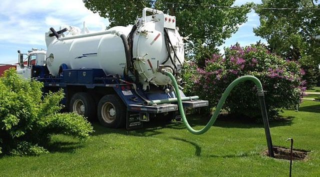 A vacuum truck is pumping water into a hole in the ground.
