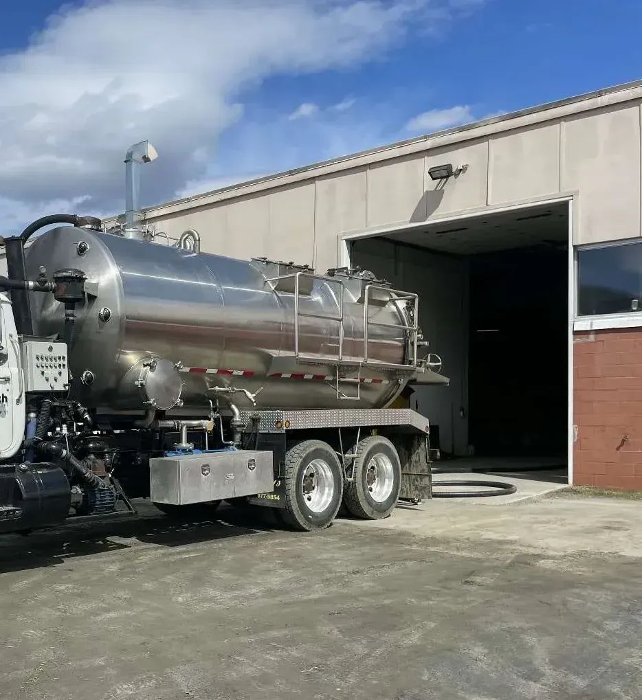 Shiny silver tanker truck parked outside a garage in daylight
