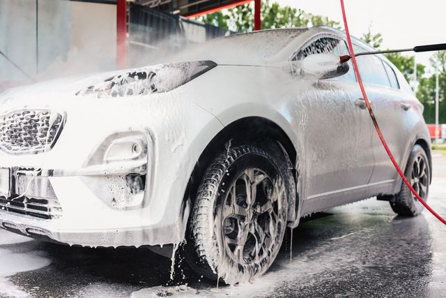 A car is being washed with foam at a car wash.