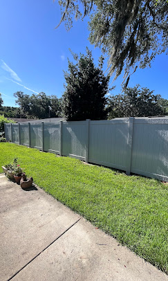 White picket fence along a grassy yard under a bright blue sky White picket fence along a grassy yard under a bright blue sky