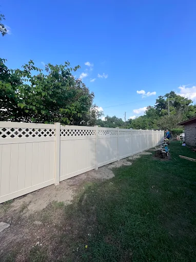 White vinyl fence bordering a grassy yard beside a rocky hillside White vinyl fence bordering a grassy yard beside a rocky hillside