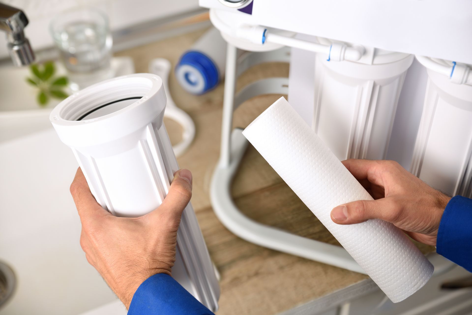 A person is holding a filter in their hands in front of a water filter.