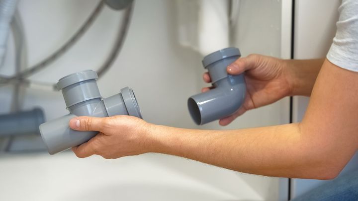 A person is holding two plastic pipes in their hands.