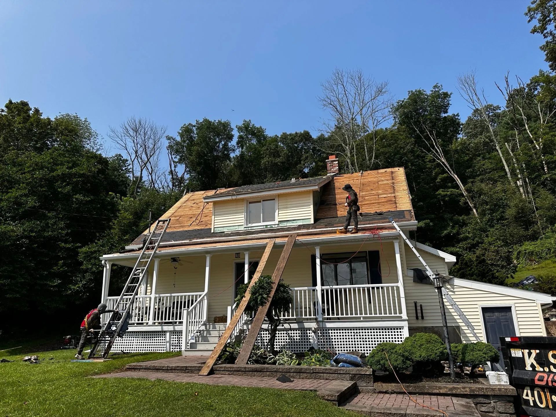 House under roof renovation, workers on roof, ladders, scaffolding, sunny day.