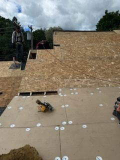 A man is standing on top of a wooden roof.