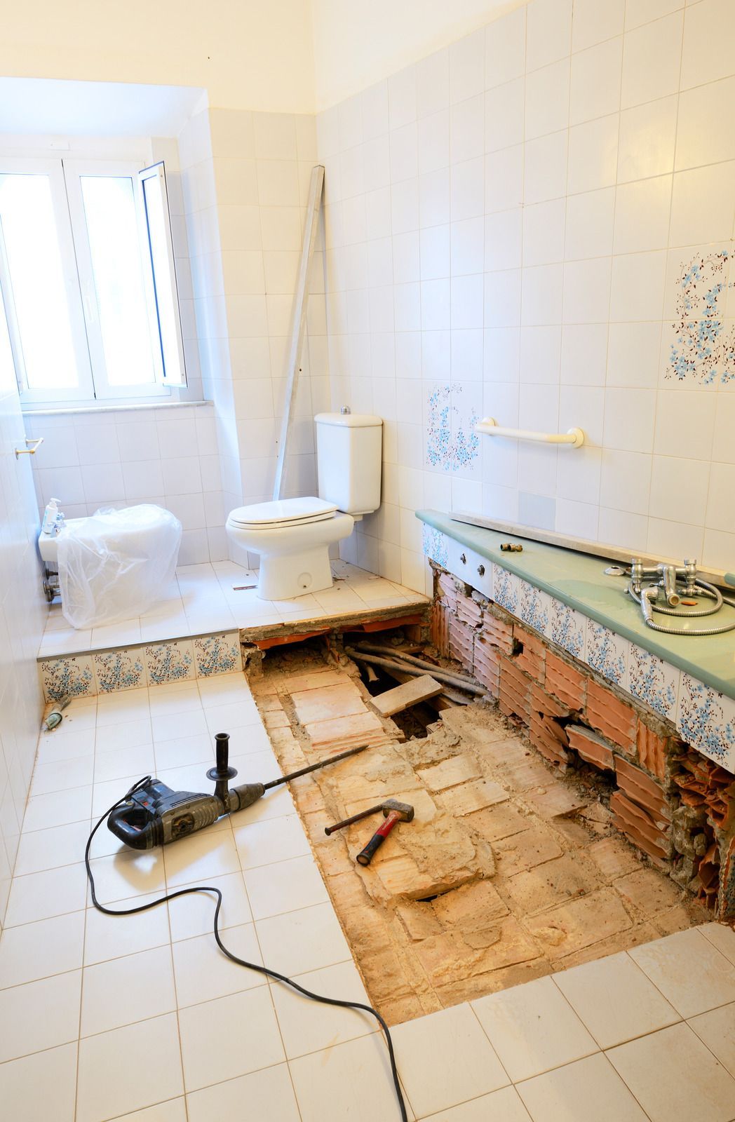 A bathroom under construction with a toilet and a drill on the floor.