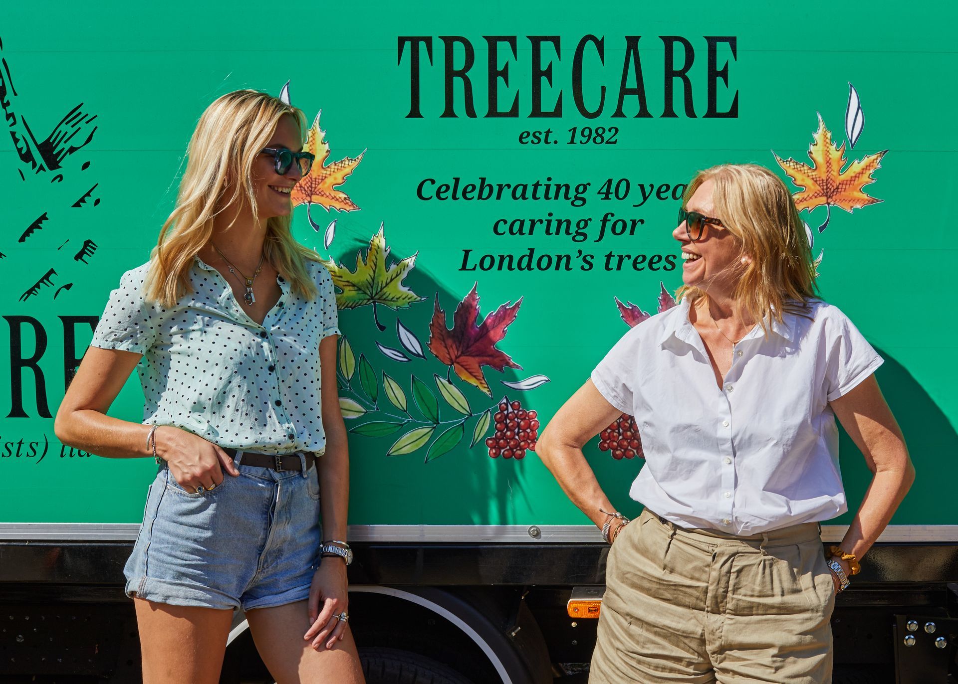 The Director of Treecare (Arboricultural Specialists) Ltd Izabella Radziwillowicz with Stephanie Radziwillowicz standing in front of a Treecare logo