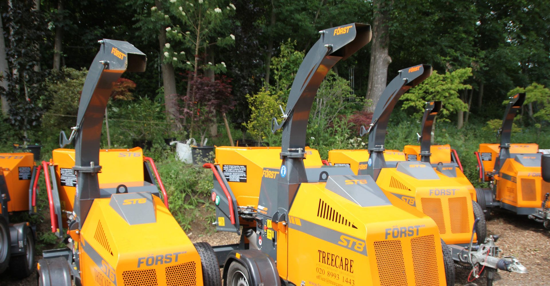 Row of orange and black Forst wood chippers outdoors.