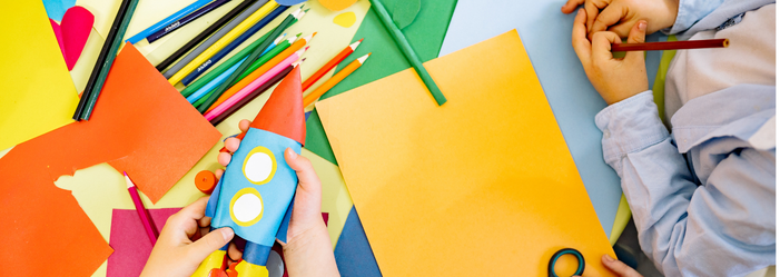 children's hands holding colouring pencils and coloured paper