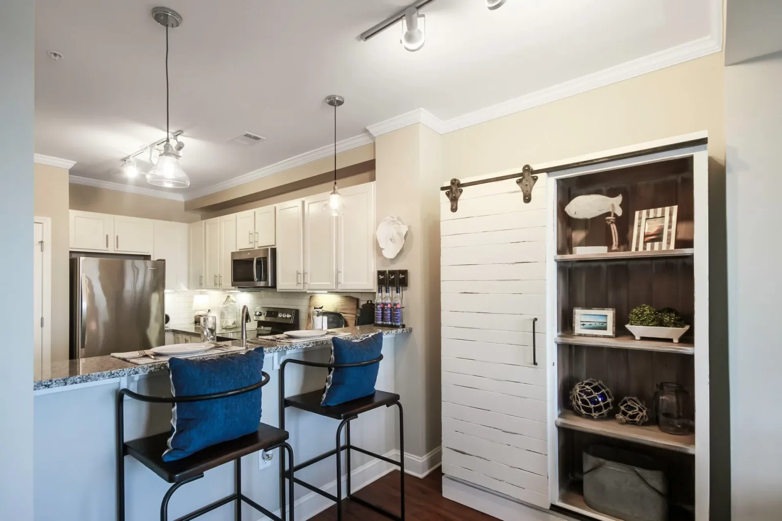A kitchen with stools and a sliding barn door at Sweetwater Apartments.