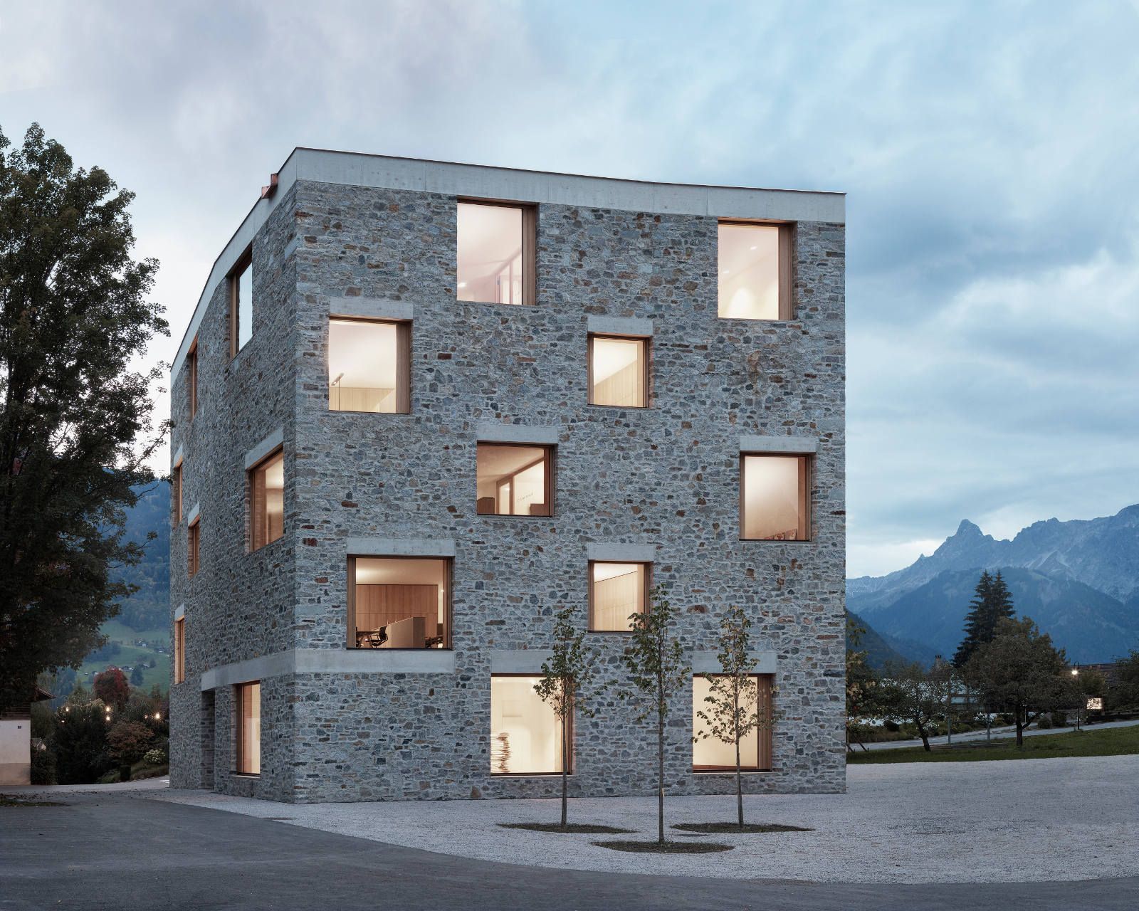 Ein Steingebäude mit vielen Fenstern und Bergen im Hintergrund