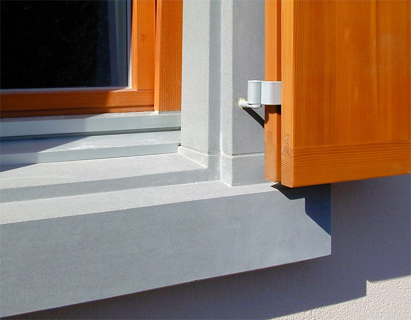 Eine Topfpflanze steht auf einem Fensterbrett neben einer Backsteinmauer.