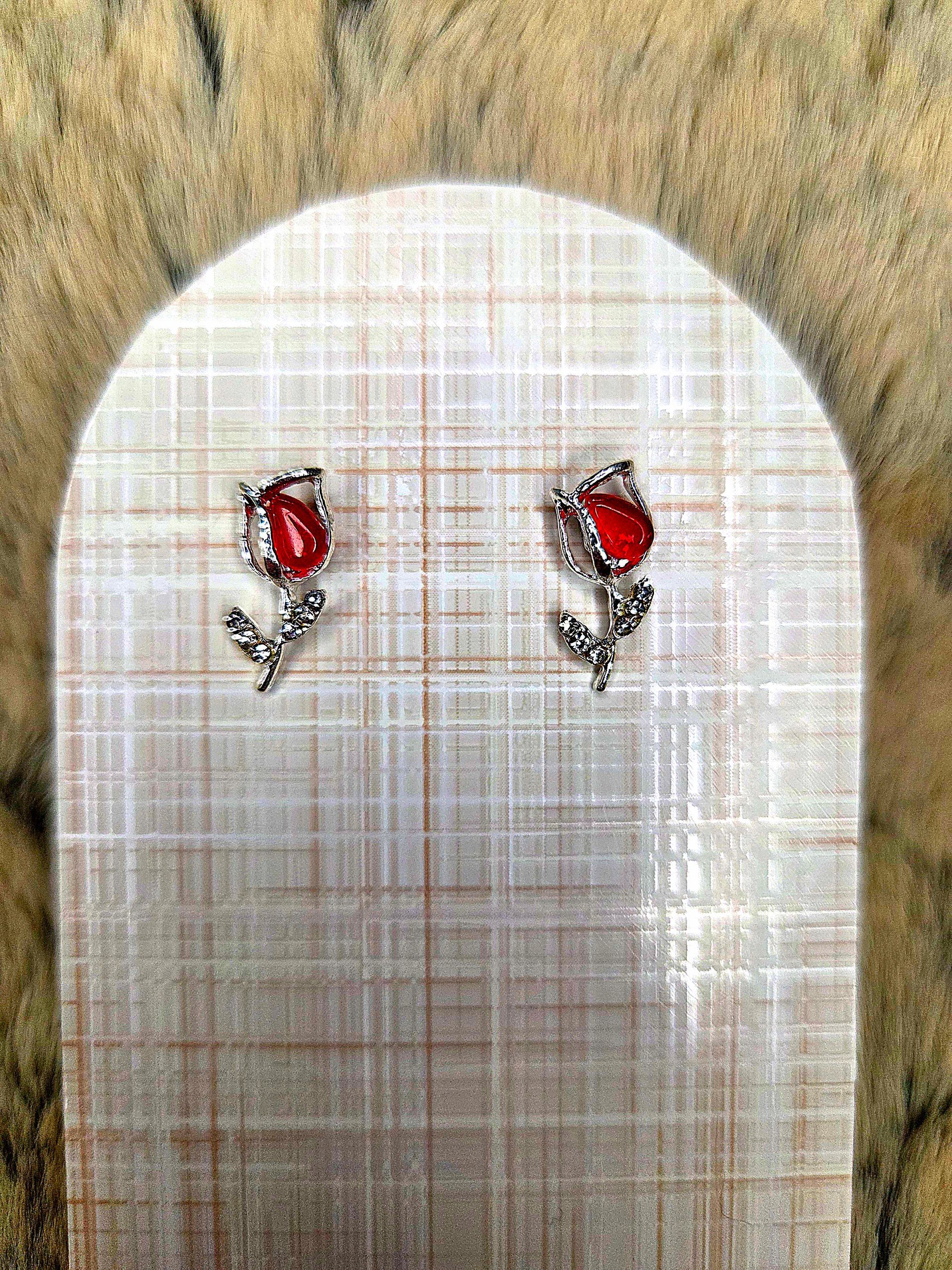 Twee kleine rood-zilveren oorbellen, vastgespeld op een wit, gestructureerd stukje stof.