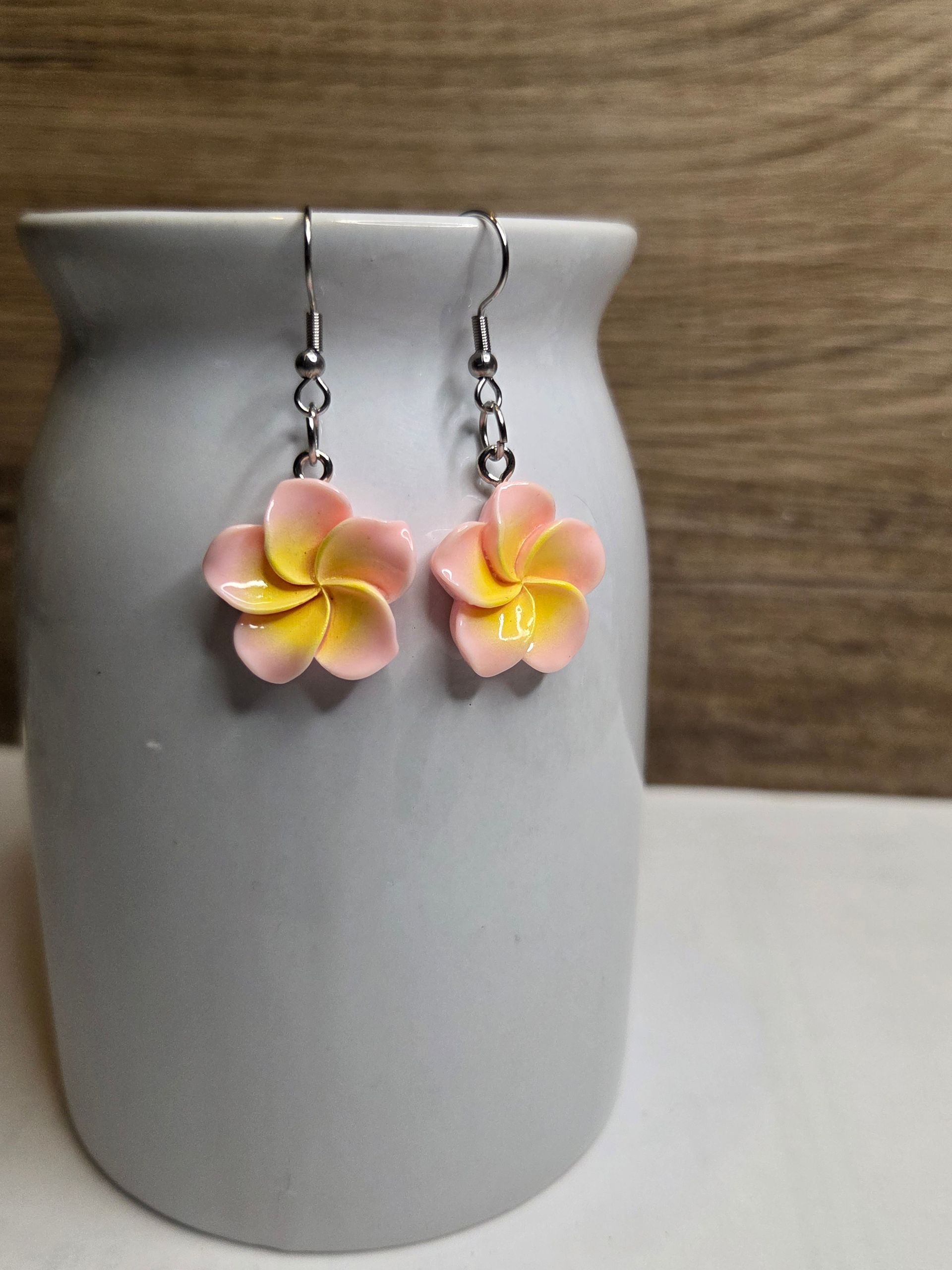Roze en gele plumeria-bloemoorbellen hangen aan een witte vaas.