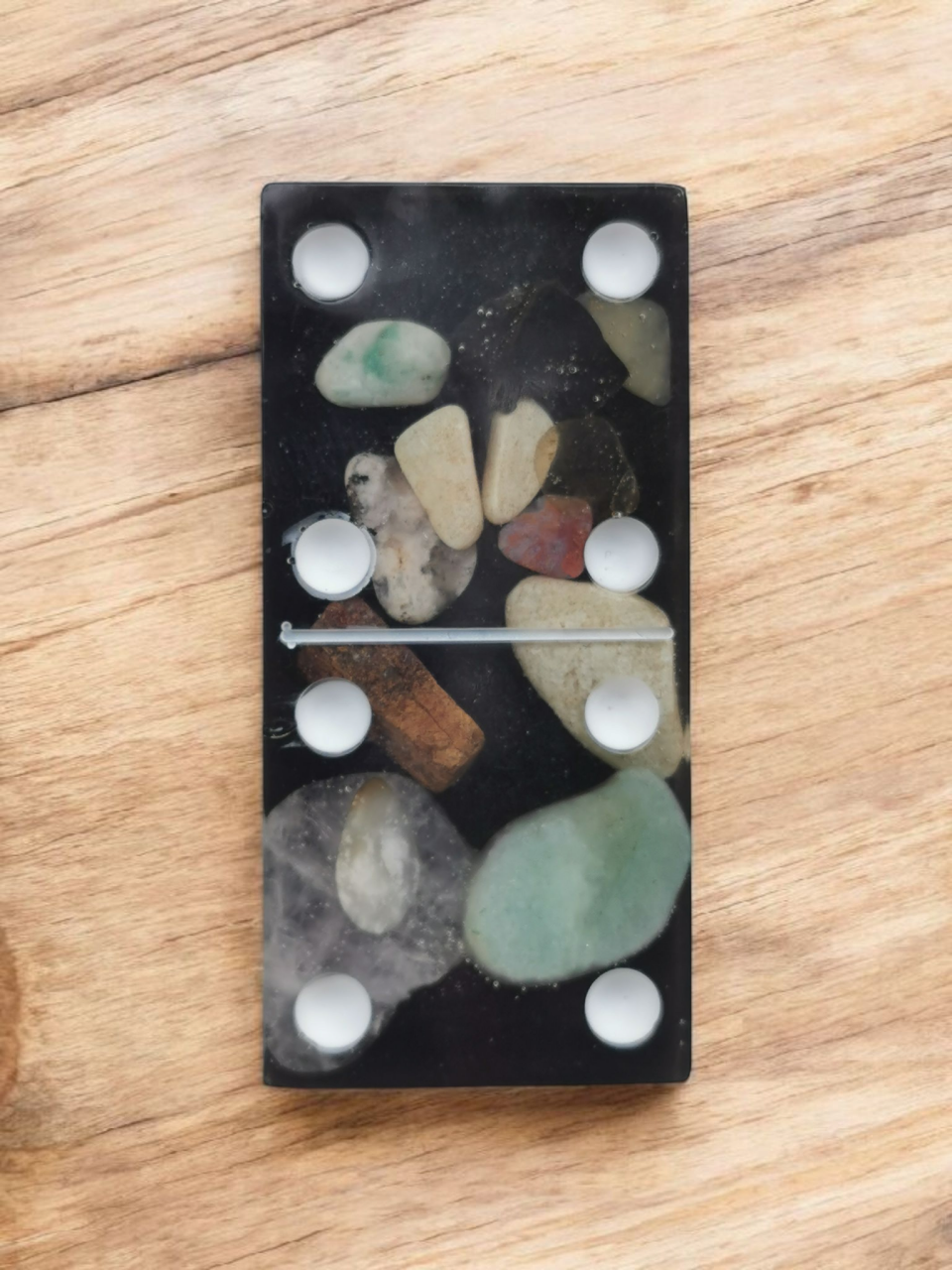 Domino met ingebedde steentjes op een houten ondergrond, waarop de cijfers 4 en 2 staan.