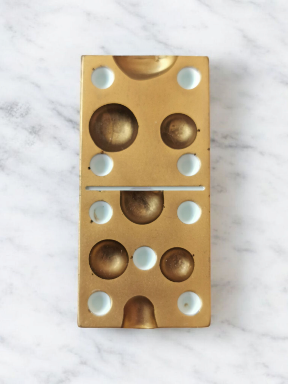 Gouden dominosteen met een marmeren achtergrond.