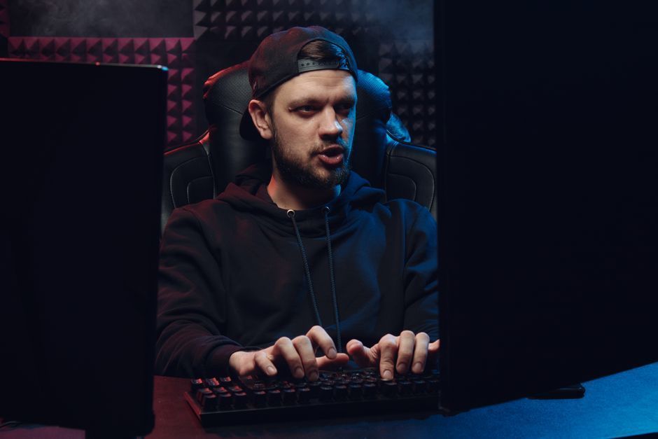 Focused gamer typing at a desktop computer in a dark neon-lit room