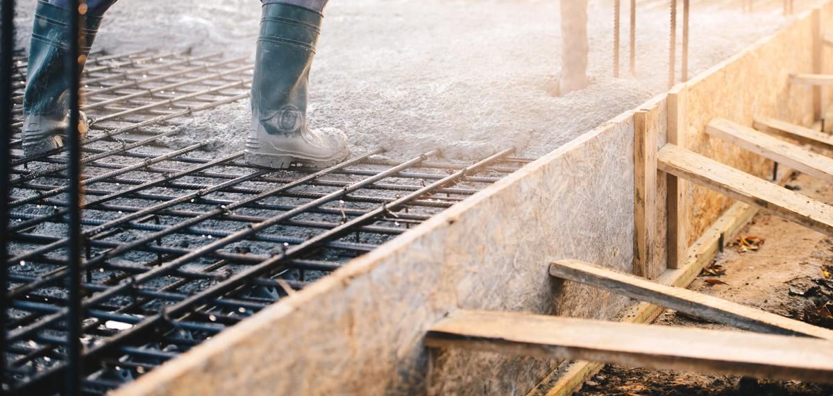 Concrete being poured over rebar on a construction site. Wooden forms are visible.