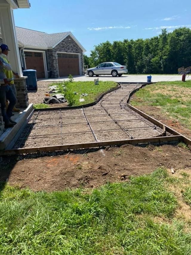 Partially built brick walkway and patio in front of a house on a sunny day