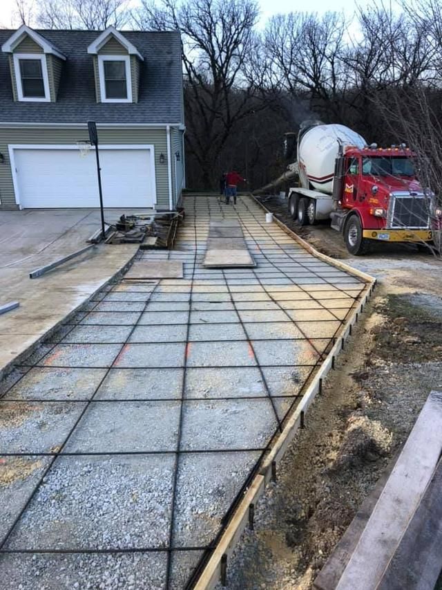 Workers smoothing wet concrete for a sidewalk with hand tools in an outdoor setting.