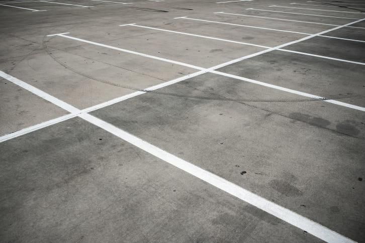 Empty parking lot with white painted lines on gray concrete.