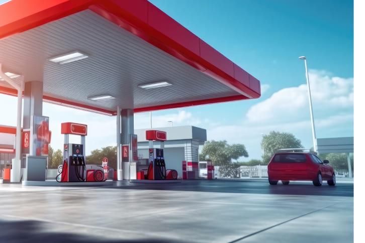 Red gas station with a red car under the canopy on a sunny day.