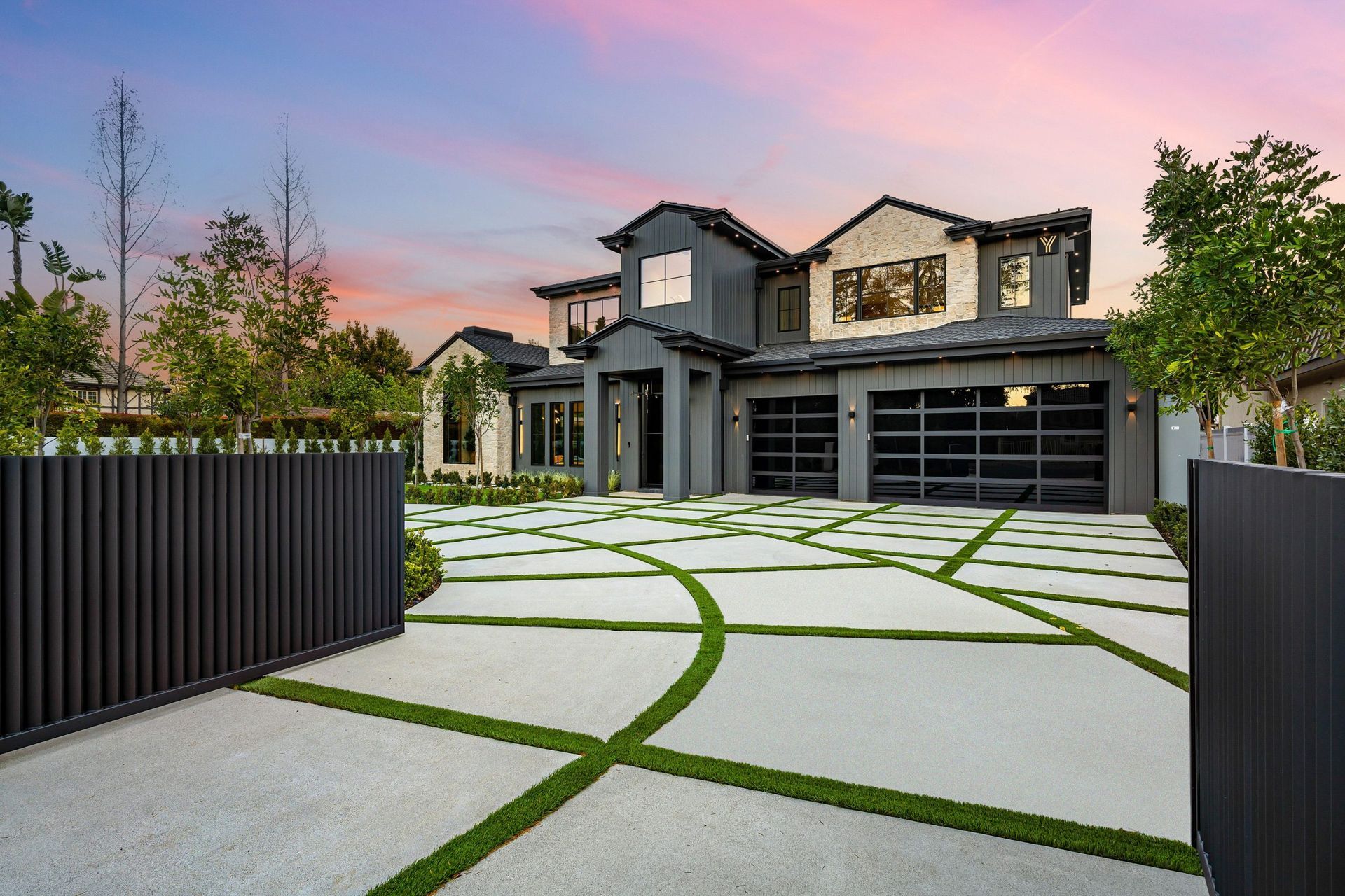 Modern luxury house with a gated driveway and patterned stone walkway at sunset