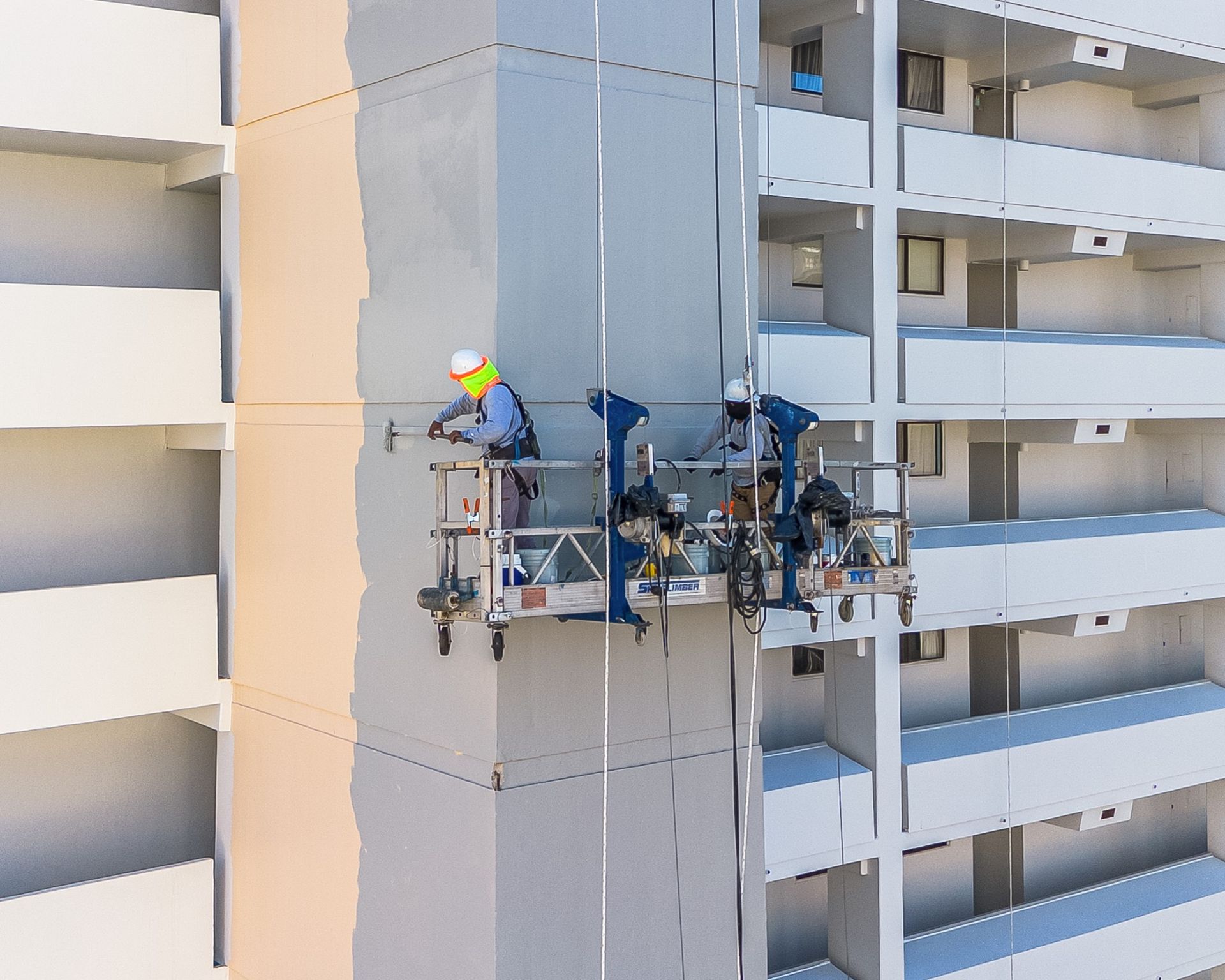 A group of men are painting the side of a building.